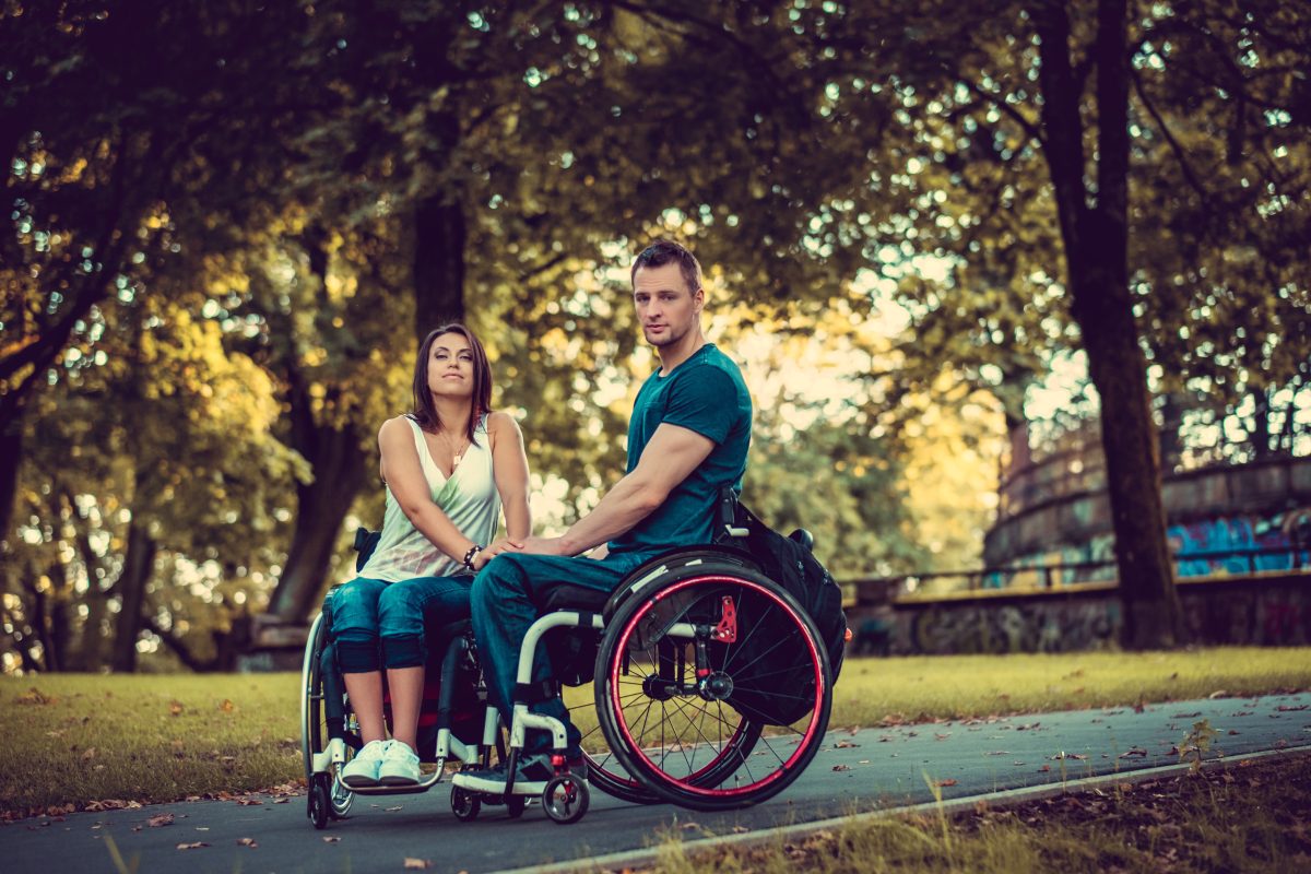 Handicapped young couple on two wheelchairs in a park in autumn.