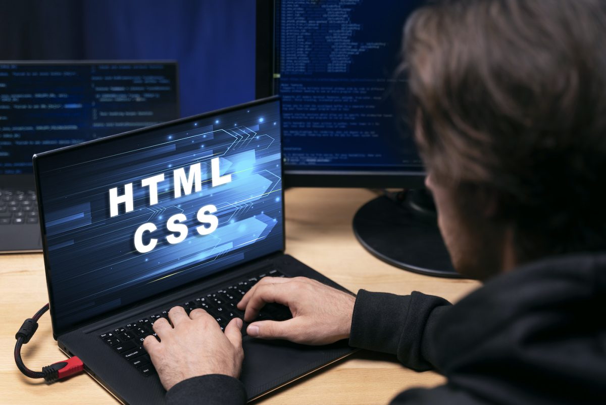 Person in front of a laptop with the words HTML and CSS. Credit: Freepik.com