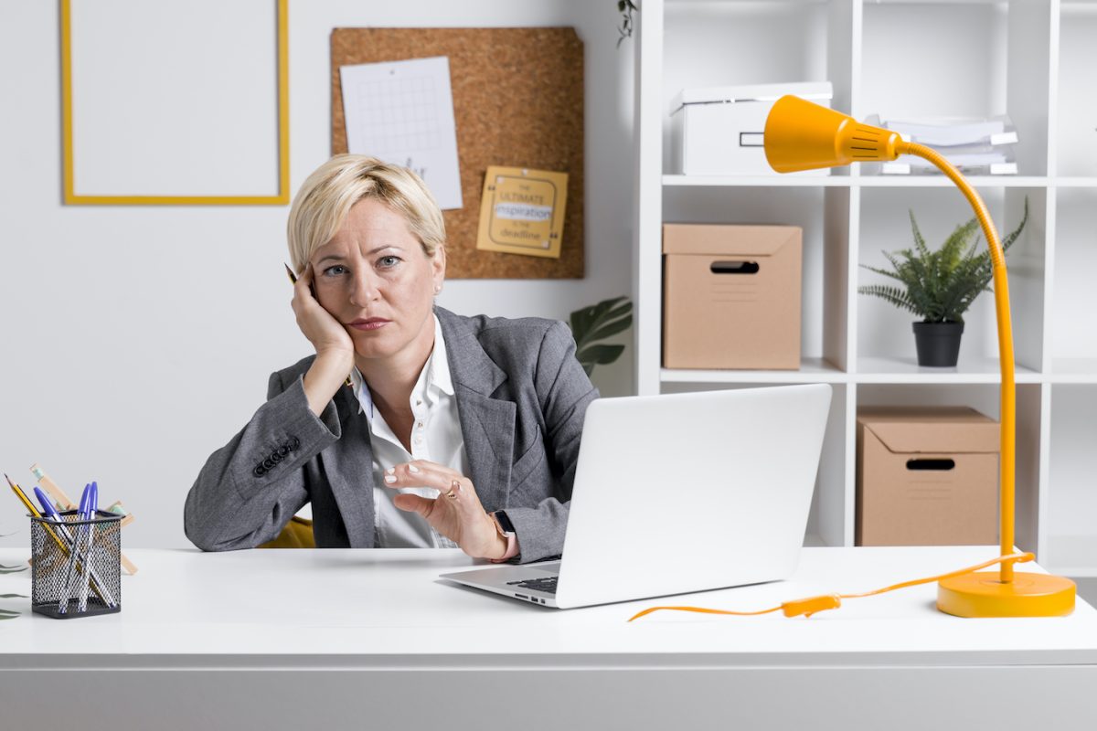 A business woman sits at a computer, lacking motivation.