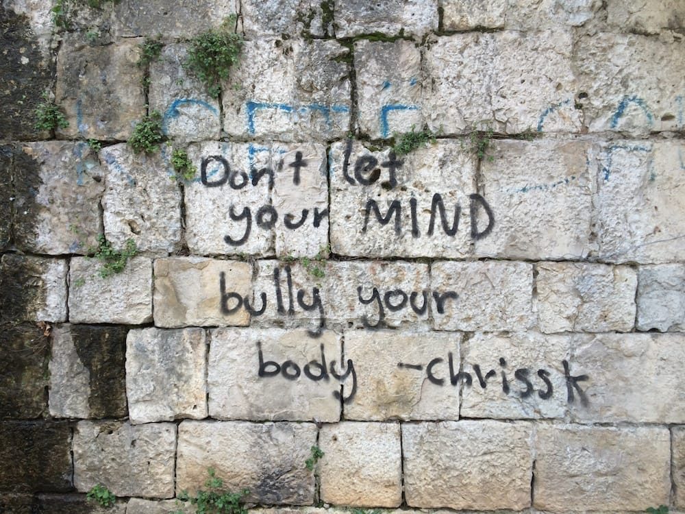 Graffiti on a stone wall, "Dont let your mind bully your body - Chriss K"